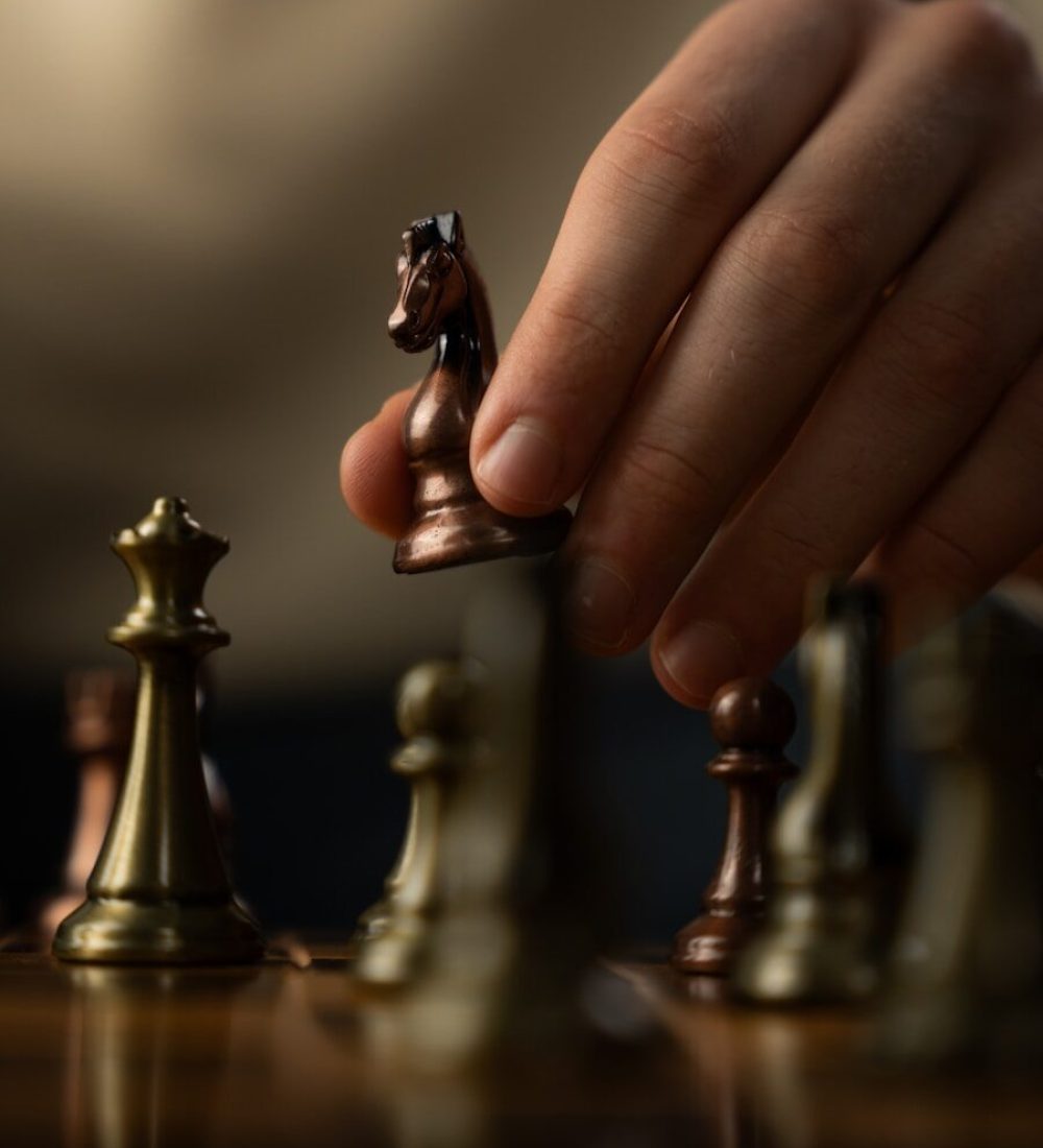 Hand moving a chess knight piece during a game.