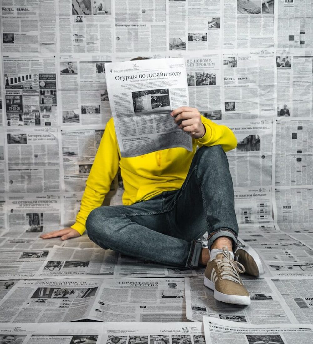 a man sitting on the floor reading a newspaper