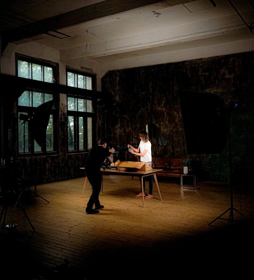 Two people setting up a product shoot indoors.